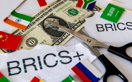 A dedollarisation concept with the words and country flags of the block of BRICS and BRICS+ countries, a pair of scissors and a US dollar bill.