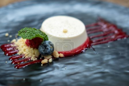 Panna Cotta served on plate with berries and sauce