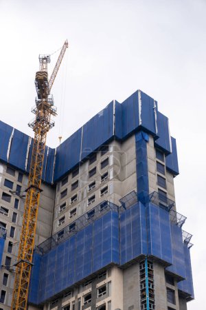 High-rise building under construction, wrapped in blue protection safety net