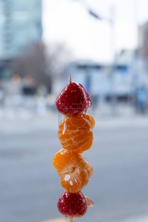 Strawberry and orange Tanghulu or Tang Hulu. It is a fruit dipped with sugar coating on a skewer. It is a traditional Northern Chinese snack.