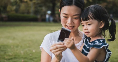 Téléchargez les photos : Jeune mère asiatique tenir fille mignonne, regarder photo polaroid avec le sourire. Maman enfant relation amoureuse ou concept enfant heureux, belle famille ensemble moment - en image libre de droit