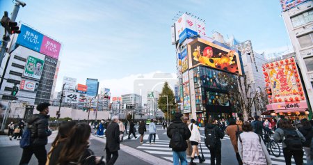 Foto de Tokio, Japón - Dec 2, 2022: Gente abarrotada camina a través de la carretera, el transporte de tráfico de automóviles en el distrito comercial de Shinjuku. Atracción turística punto de referencia turístico, transporte de Asia o la vida de ciudad asiática - Imagen libre de derechos