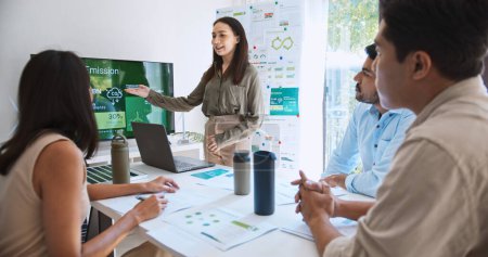 Une femme asiatique dirige un jeune groupe d'hommes d'affaires multiethniques lors d'une réunion d'équipe, en utilisant un ordinateur portable pour la présentation du sujet ESG sur moniteur. Pratique d'entreprise durable, les gens travaillent à la maison concept