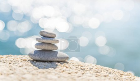 Pyramid stones on the seashore on a sunny day on the blue sea background. Happy holidays. Pebble beach, calm sea, travel destination. Concept of happy vacation on the sea, meditation, spa, calmness.