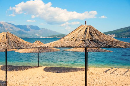 Téléchargez les photos : Parasols de plage en matière naturelle - paille contre le soleil - un paradis de détente - en image libre de droit
