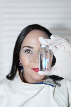 Photo for Woman scientist in bio molecular research holds in her hands a vial of biomolecular medicine copied from human DNA RNA - Royalty Free Image