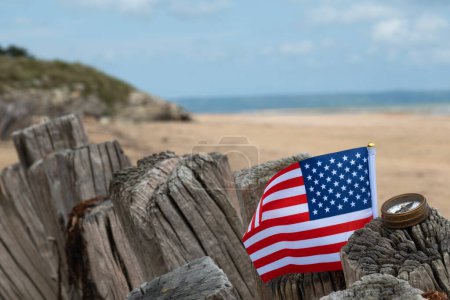 Utah Beach WWII mit Flagge der USA und Kompass im scharfen Fokus mit Strand und Meer im Hintergrund. Sandstrand und Zaunpfähle. In der Normandie erinnert Frankreich an den Veteranentag. Hochwertiges Foto