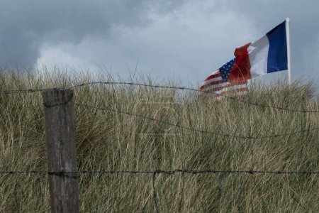 Zona Normandía de la playa de Utah. Bandera Revolucionaria francesa, estadounidense y francesa ondean. Cielo nublado. Foto de alta calidad