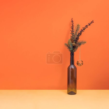 Foto de La composición mínima invernal de las fiestas con una rama decorativa en la botella. Concepto de Navidad y Año Nuevo. - Imagen libre de derechos