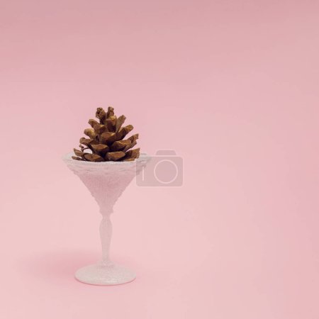 Téléchargez les photos : Un cône de pin dans un verre gelé sur fond rose pastel. Composition minimaliste des vacances d'hiver, concept Noël et Nouvel An. - en image libre de droit