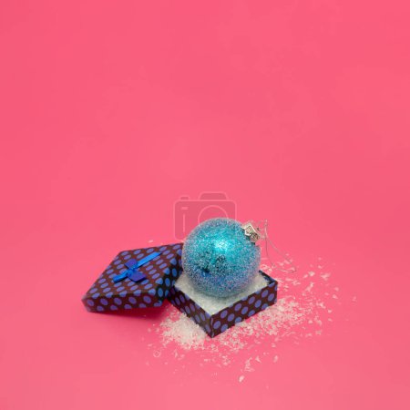 Téléchargez les photos : Minimale boule de Noël bleue enneigée dans une boîte cadeau sur fond rose pastel. Hiver HOliday concept. - en image libre de droit