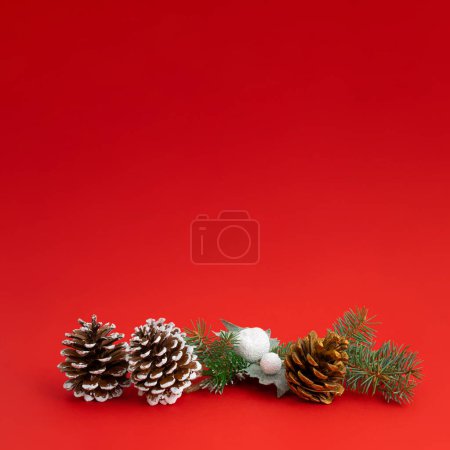 Foto de Fondo rojo de Navidad con decoración de invierno, ramas de árboles y conos de pino. Diseño de espacio de copia de vacaciones. - Imagen libre de derechos