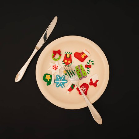 Téléchargez les photos : Concept de dîner de Noël. Ornements de Noël colorés dans une assiette sur un fond noir. Noël et Nouvel An fond. - en image libre de droit