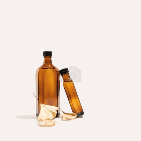 Foto de Ginkgo biloba essential extract in a bottle and golden leaves. Minimal neutral herbal or natural medicine arrangement. Ginkgo biloba. - Imagen libre de derechos