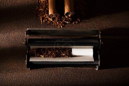 Photo for Hand-rolled cigarette, rolling machine, cigarillos, scattered tobacco on background, cigarette roll with filter, cigarette filters - Royalty Free Image