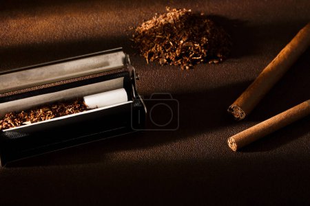 Photo for Hand-rolled cigarette, rolling machine, cigarillos, scattered tobacco on background, cigarette roll with filter, cigarette filters - Royalty Free Image