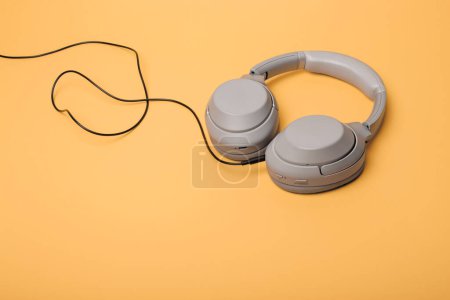 Téléchargez les photos : Light gray wireless on-ear headphones with the ability to connect via wire on a peach background. Headphones for playing games or listening to music. Noise canceling headphones. Top view. Copy space - en image libre de droit