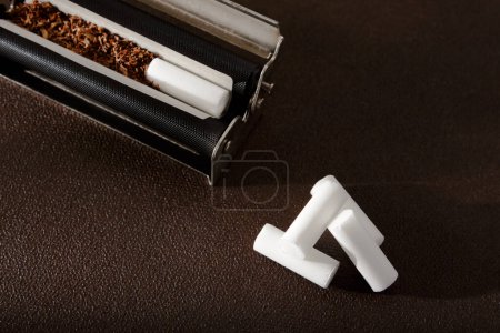 Photo for Hand-rolled cigarette, rolling machine, scattered tobacco on background, cigarette roll with filter, cigarette filters - Royalty Free Image