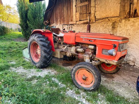 Photo for Menthon saint Bernard, France - October 23 2021: a rusted vintage tractor is parked next to a farm on the french countryside and is a zetor 4511 model - Royalty Free Image