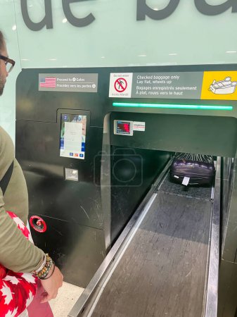 Foto de Toronto, canada - 26 october 2022: a passenger at an airport has self checked his bag for his flight and sees his luggage on a conveyor belt - Imagen libre de derechos