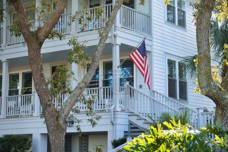 Foto de Charleston, Estados Unidos - 5 de noviembre de 2022: antigua propiedad histórica de playa con veranda y estrellas americanas y bandera de rayas - Imagen libre de derechos