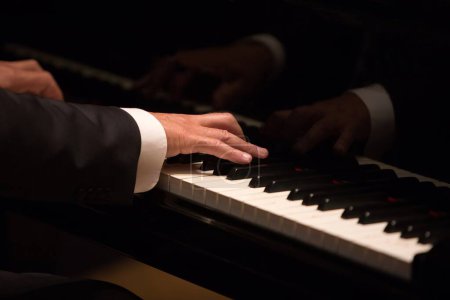 Téléchargez les photos : Pianiste joue sur un piano à queue avec des réflexions sur l'instrument classique élégant - en image libre de droit