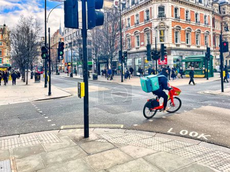 Photo for London, United Kingdom - March 07 2022: a food delivery person on a bicycle is driving on Oxford street - Royalty Free Image