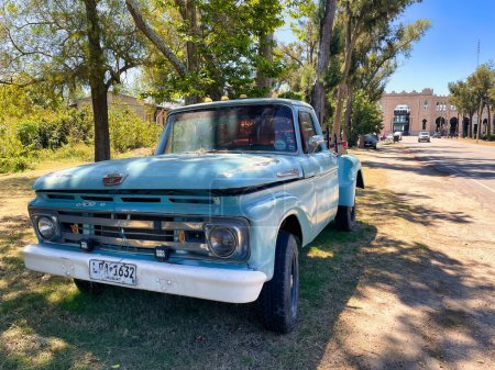 Foto de Colonia del sacramento, uruguay - 2 de noviembre de 2022: una furgoneta vintage de color azul oxidado f-100 1960s recoger camión estacionado a lo largo de la carretera - Imagen libre de derechos