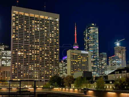 Foto de Toronto, Canadá - 24 de octubre de 2022: edificios de gran altura que forman el horizonte de la ciudad por la noche con la torre cn en colores neón - Imagen libre de derechos
