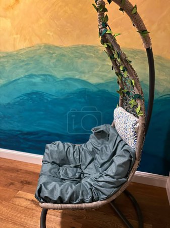 Photo for Den haag, netherlands - august 07 2023: a birdnest hanging chair has been placed indoor in a nursery room with a colourful design wall as backdrop - Royalty Free Image
