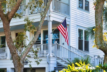 Foto de Charleston, Estados Unidos - 5 de noviembre de 2022: antigua propiedad histórica de playa con veranda y estrellas americanas y bandera de rayas - Imagen libre de derechos