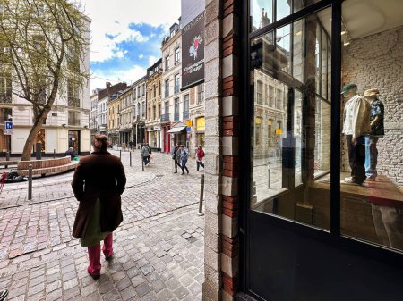 Téléchargez les photos : Lille, France - 12 avril 2023 : une personne est vue dans une rue commerçante de la vieille ville et une devanture - en image libre de droit