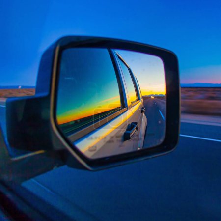 Photo for Las Vegas, United States - February 22 , 2013 : a side rear mirror of a car looking to the back, the evening night while the sunhas set over the desert between las vegas to los angeles - Royalty Free Image