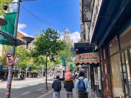 Téléchargez les photos : Montevideo, uruguay - 31 octobre 2022 : une famille marche sur le trottoir de l'avenue de 18 julio rue commerçante avec un petit enfant sur les épaules - en image libre de droit