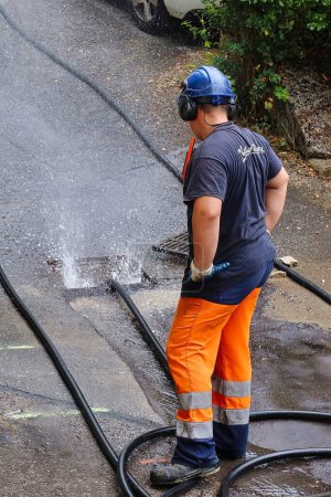 Photo for Menthon Saint Bernard, France - September 09 2021: a professional worker is busy with a pump car and a hose under high pressure cleaning a sewer tube - Royalty Free Image