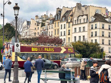 Photo for Paris, France - April 11 2023: a tour bus passes by on a busy street with a lot of people and parisian haussmann buildings - Royalty Free Image