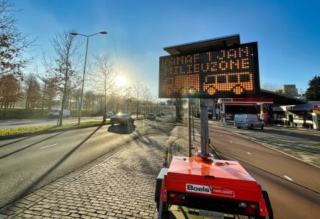 Téléchargez les photos : Den Haag, Pays-Bas - 16 décembre 2021 : un panneau routier numérique mobile placé à côté d'une entrée dans une ville indique qu'une zone propre est interdite pour les voitures et camions lourds polluants - en image libre de droit