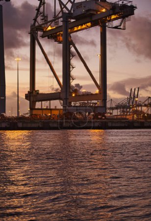 Foto de Rotterdam, Países Bajos - 11 de noviembre de 2021: los contenedores marítimos se descargan de los buques por grúas enormes - Imagen libre de derechos