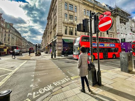 Téléchargez les photos : Londres, Royaume-Uni - 7 mars 2022 : les gens marchent sur le trottoir et attendent avant de traverser une rue près de Cavendish place - en image libre de droit