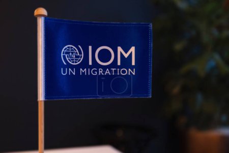 Téléchargez les photos : La Haye, Pays-Bas - 08 février 2024 : un drapeau bleu avec le logo de l'Organisation des Nations Unies pour les migrations l'OIM sur un bureau dans un bureau - en image libre de droit
