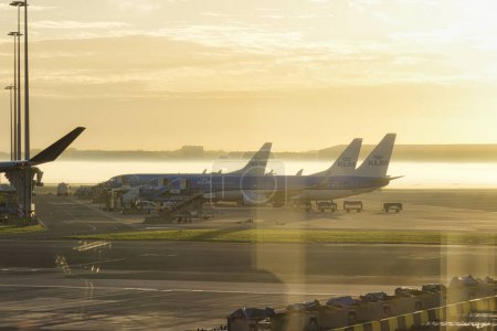 Téléchargez les photos : Amsterdam, Pays-Bas - 18 octobre 2022 : avions de klm sur la plate-forme d'un aéroport tôt le matin avec coucher de soleil et brouillard - en image libre de droit
