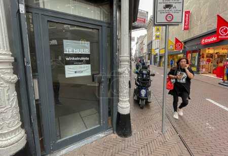 Photo for Den Haag, Netherlands - July 27 2021: people walking in city strete passing an emty store with a for rent sign - Royalty Free Image