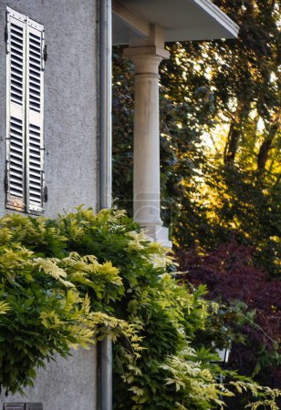 Foto de Talloires, Francia - 08 de septiembre 2020: una antigua casa histórica con persianas, balcón con una columna y hiedra creciendo en la pared exterior - Imagen libre de derechos