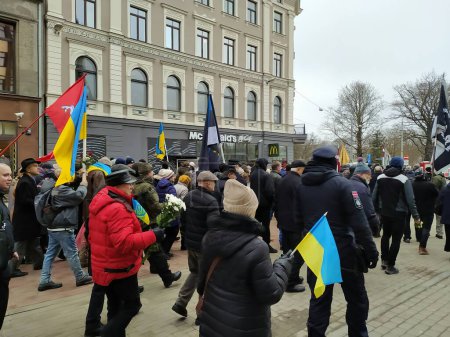 Foto de Letonia, Riga, 16.03.2023. Una memorable procesión de legionarios letones "Waffen-SS" en el centro de Riga bajo la protección de las fuerzas especiales de la policía. Los ucranianos que recibieron asilo en Letonia participaron en la marcha. - Imagen libre de derechos