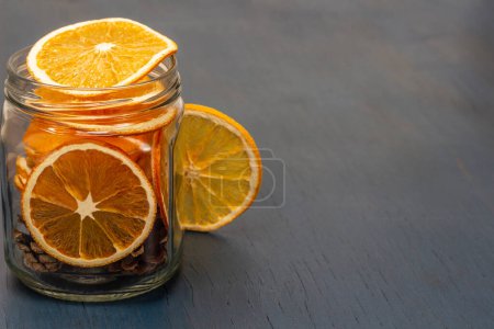 Photo for Dry orange slices and fir cones in glass jar. Christmas decorations. Copy space. Top view. Blue background. - Royalty Free Image