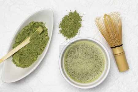 Photo for Bamboo scoop in a bowl of matcha powder. Matcha green tea in a bowl. Bamboo whisk on the table. Flat lay. White background - Royalty Free Image