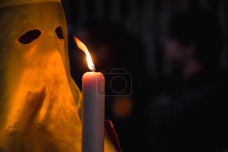 Eine Person in einem gelben Kostüm steht neben einer Kerze mit dem Wort Licht darauf.