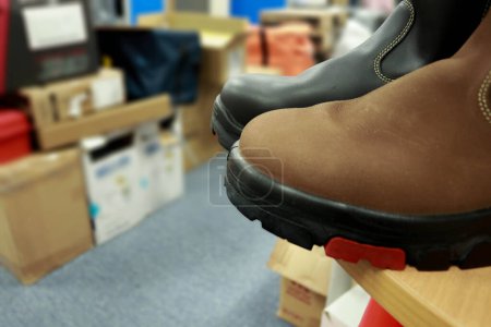 Foto de Foto de zapatos de seguridad de cuero marrón y negro en la mesa del almacén - Imagen libre de derechos