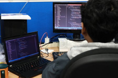 Foto de Los programadores están haciendo su trabajo frente a una computadora llena de lenguajes de programación en una oficina - Imagen libre de derechos