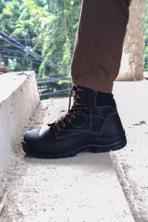 Foto de Un trabajador de la construcción lleva botas de cuero marrón que se ve muy fresco y de moda - Imagen libre de derechos